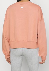 Överdimensionerad, kort sweatshirt i ljusrosa, tillverkad av mjukt material. Har ribbade muddar och nederkant, med en liten Nike-logotyp på baksidan.