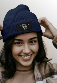 Navy knit beanie featuring a black patch with the text "valhalla" and crossed axes design. Soft texture, cuffed design for snug fit.