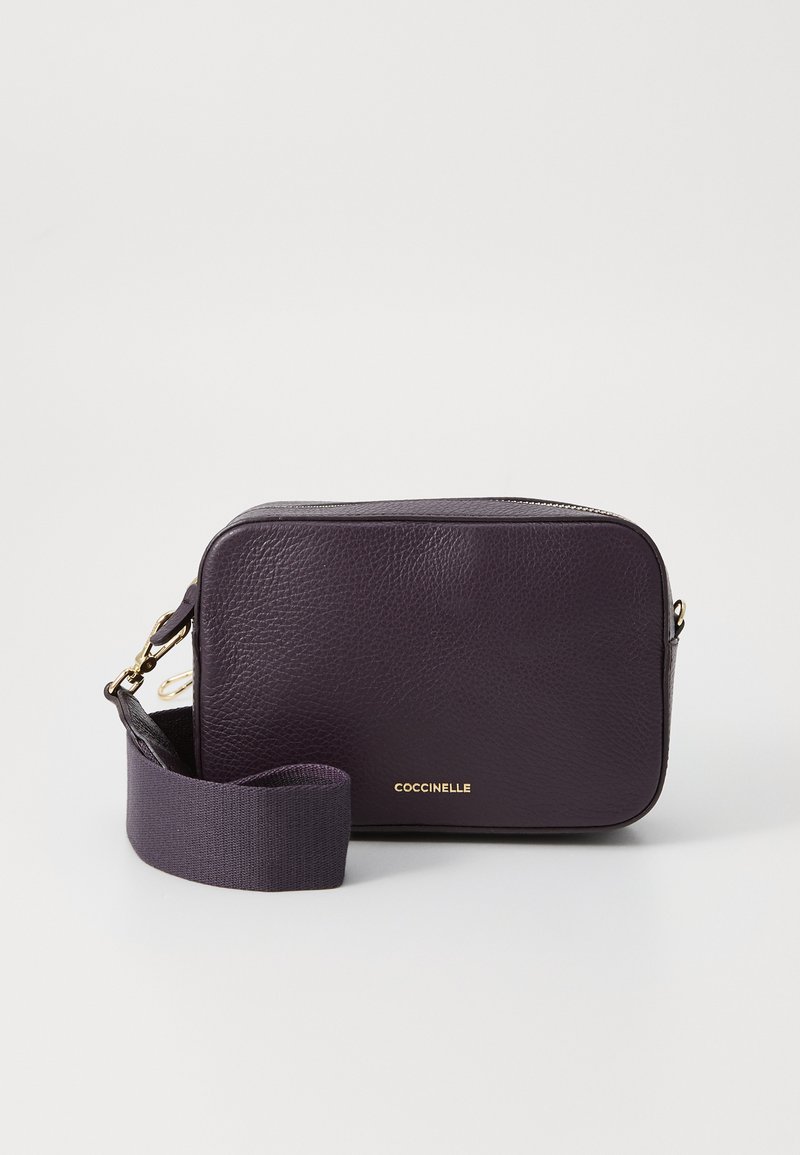 Purple leather crossbody bag with a textured surface, zip closure, and gold logo detailing. Features a woven strap for easy carrying.
