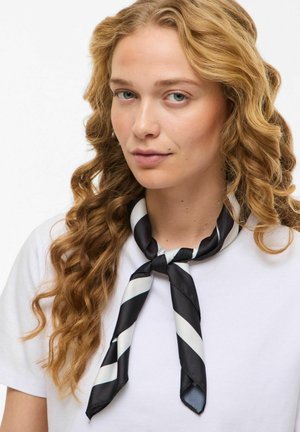 Écharpe en soie à rayures noires et blanches nouée autour du cou, présentant une texture lisse et une finition brillante.