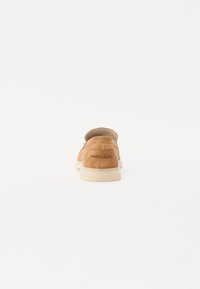 Brune semskede slip-on sko med en glat overflade, hvid gummisål og minimale syninger. Bagview fremhæver formen og designet.
