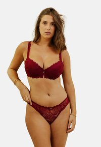 Ensemble soutien-gorge et string en dentelle bordeaux avec motif floral, bordures festonnées et un petit accent doré au centre avant du soutien-gorge.