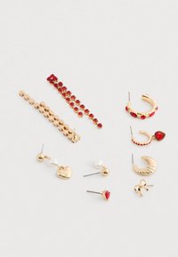 Sett med gullfargede øreringer med ulike design: hjerte, halvmåne, ring og stift-stiler med røde juveldetaljer og perledetaljer.