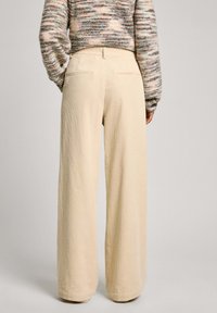 Beige wide-leg pants with a textured fabric. Features two back pockets and a relaxed fit. Suitable for casual wear.