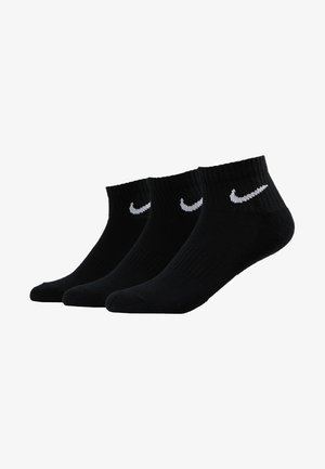 Chaussettes noires à la cheville en paquet de trois, fabriquées en matériau côtelé, avec un logo Nike en blanc sur chaque chaussette.