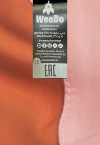 Etichetta che mostra "WeeDo", progettato in Germania, presenta un tessuto arancione e rosa, indicando una colonna d'acqua di 10K e una traspirabilità di 5K. Etichetta EAC inclusa.