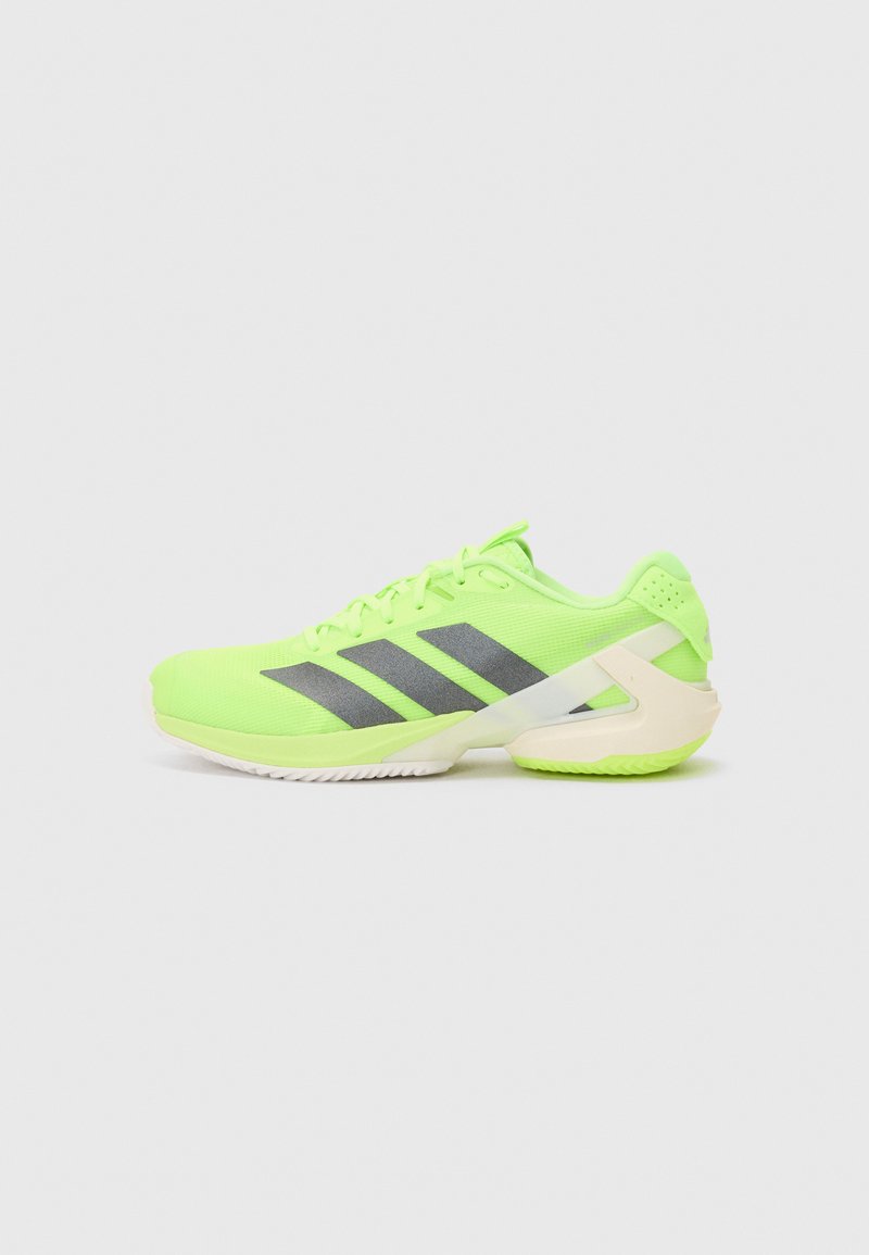 Neon zielone buty sportowe z szarymi paskami, teksturowana siateczka na górze, biała podeszwa i charakterystyczny design pięty. Sznurowadła w kolorze buta.