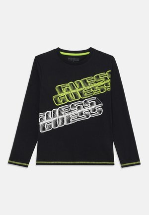 Czarna koszula z długim rękawem z dwoma ukośnymi logo "GUESS" w neonowo-żółtym i białym kolorze, z zielonym przeszyciem na mankietach i u dołu.