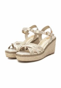 Sandalias de cuña con parte superior en dorado metálico, tiras entrecruzadas y detalles cortados a láser. Cuentan con una suela de yute estilo espadrille.