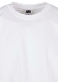 T-shirt bianco in cotone con collo rotondo, dotato di un'etichetta interna che recita "URBAN CLASSICS M." Texture morbida, senza pattern visibili.