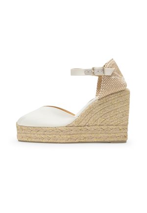 Sandalia cuña blanca con punta cerrada, plataforma trenzada de yute, tira en el tobillo con hebilla y contrafuerte en el talón beige con estampado.