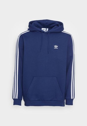 Marineblaue Adidas Kapuzenjacke mit weißen drei Streifen an den Ärmeln, Fronttasche, Kapuze und kleinem Adidas-Logo auf der Brust.