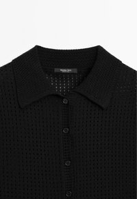 Zwarte gebreide cardigan met een geperforeerde textuur, een kraaghals en zes knopsluitingen met gladde zwarte knopen.