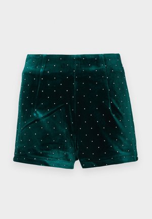 Pantalones cortos de terciopelo verde con tachuelas plateadas, pliegues estructurados y una textura suave. Diseñados para una silueta ajustada.