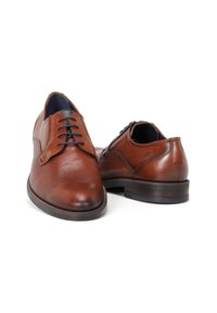 Zapatos de cuero marrón con un acabado texturizado, punta redondeada y diseño tradicional de cordones, con una suela suave y detalles sutiles.