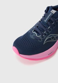 Bottillon de sport bleu marine avec une tige en mesh respirant, accent de semelle rose et détails gris sur les côtés. Présente un bout arrondi et des lacets.