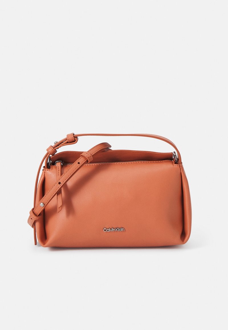 Petit sac bandoulière rectangulaire en cuir lisse coloris camel avec sangle ajustable et logo Calvin Klein argenté à l'avant.
