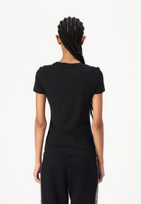 Black fitted t-shirt with short sleeves and a crew neck, made from smooth cotton fabric, displayed from the back.