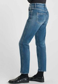 Blauwe denim jeans met een rechte pijpdesign, lichte vervaging en twee achterzakken. Draag ze met zwarte schoenen en sokken.