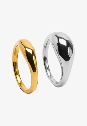 Dwa gładkie, polerowane pierścienie o nowoczesnym, zakrzywionym kształcie; jeden złoty, drugi srebrny, prezentowane na białym tle.