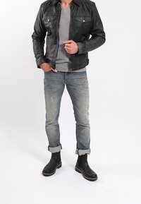 Černá kožená bunda, šed�é tričko s V výstřihem, džíny s lehkým praním s ohrnutými nohavicemi, černé kotníkové boty s texturovanou podrážkou.