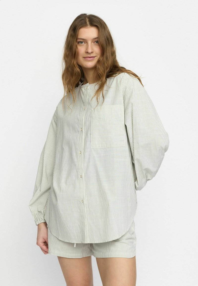 Gestreifte Hemdbluse in Hellgrün und Weiß. Lange Ärmel, abgerundeter Saum und Brusttasche. Kombiniert mit passenden Shorts.