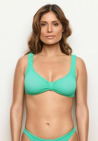 Turkos texturerad bikiniöverdel med breda band och central samlingsdetalj, tillsammans med matchande underdelar som visar en enfärgad design.