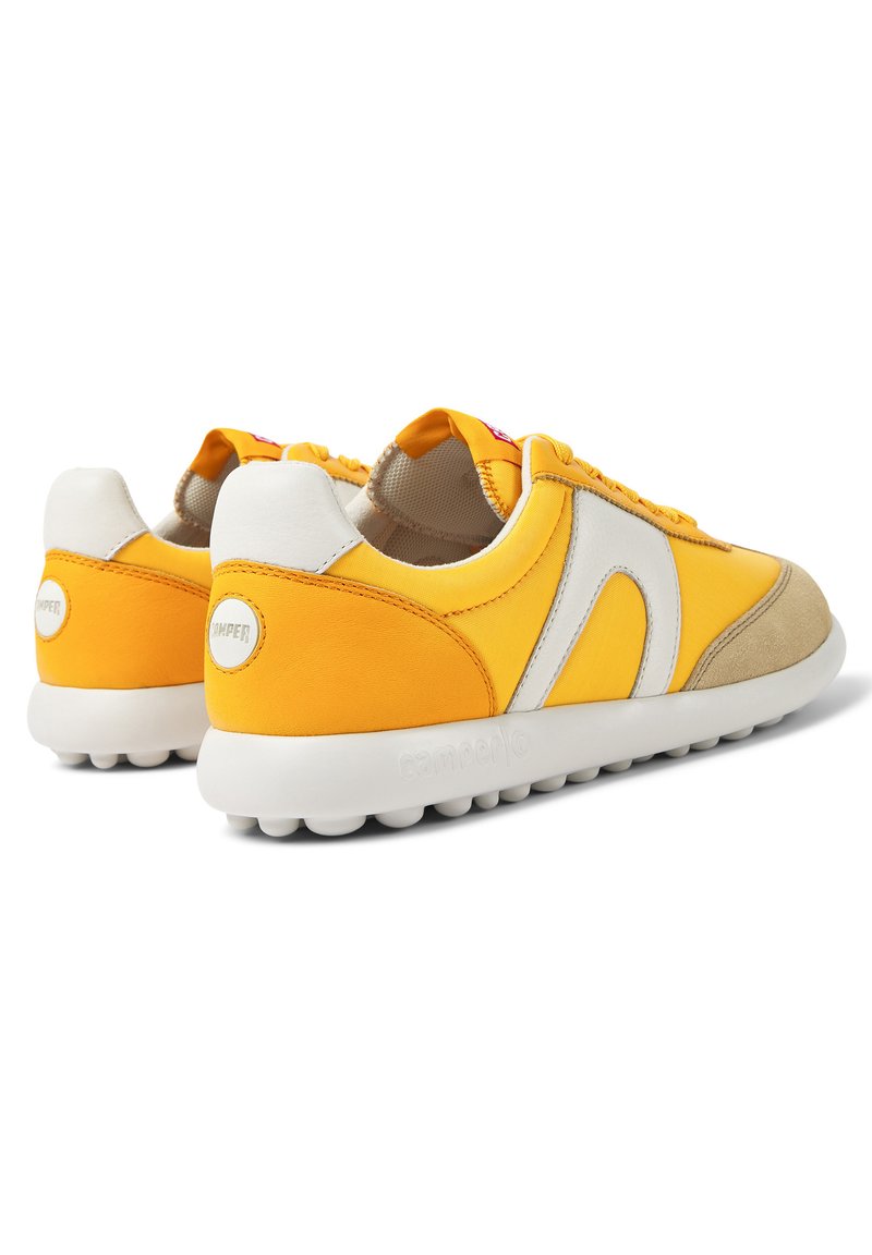 Zapatillas amarillas con parte superior de malla, acentos de ante y goma, que presentan una entresuela blanca elevada y una suela texturizada para agarre.