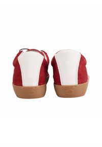 Baskets en suède rouge avec des accents en cuir blanc. Présentent un bout arrondi, une texture douce et une semelle en caoutchouc beige avec un détail d'empreinte de lèvre.