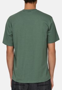 Green cotton t-shirt with short sleeves, a crew neckline, and a smooth texture. No graphics or patterns are visible.