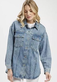 Jasnoniebieska koszula dżinsowa z długimi rękawami, dwoma kieszeniami na piersi, zapięciem na guziki oraz szczegółami wykończenia. Posiada luźny krój i zaokrąglony dół.