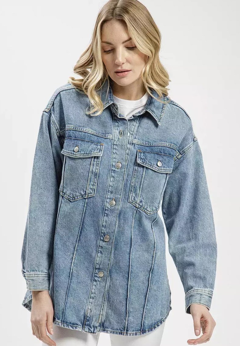 Jasnoniebieska koszula dżinsowa z długimi rękawami, dwoma kieszeniami na piersi, zapięciem na guziki oraz szczegółami wykończenia. Posiada luźny krój i zaokrąglony dół.