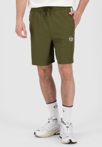 Olivgrüne Shorts mit einem elastischen Bund und Kordelzug. Besticktes Logo auf dem linken Bein. Glattes Material, knielange Passform.
