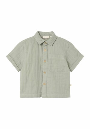 Short-sleeve button-up shirt in light green cotton with a front pocket, wooden buttons, and a collared neckline. Soft texture and relaxed fit.