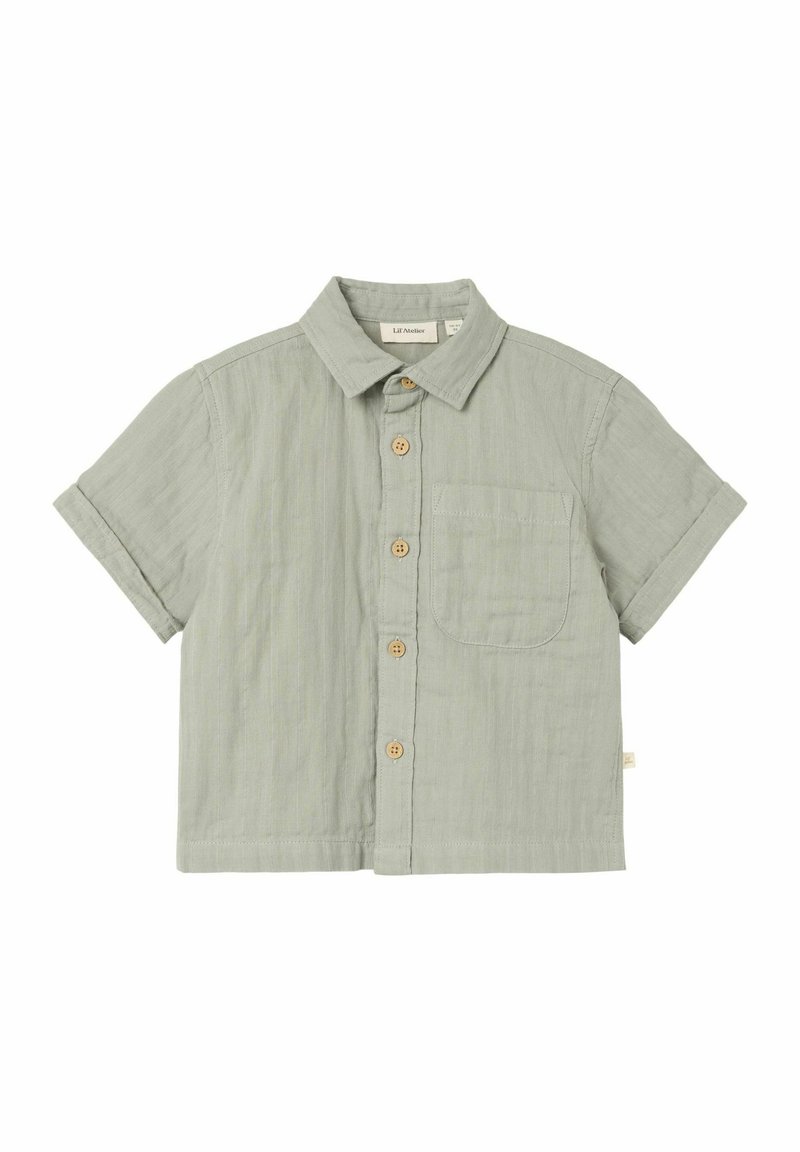Camicia a maniche corte in cotone verde chiaro con taschino frontale, bottoni in legno e colletto. Texture morbida e vestibilità rilassata.