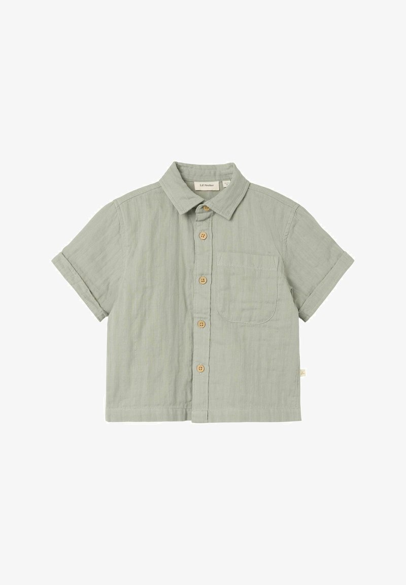 Lühikese varrukaga nööbiga särk helesinisest puuvillast, millel on ees tasku, puidust nööbid ja kaelus. Pehme tekstuur ja mugav lõige.