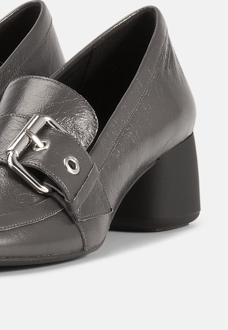 Gray leather heeled shoes featuring a buckle strap and a block heel. Smooth texture with a structured design and detailed stitching.