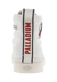 Scarpa alta bianca con colletto imbottito, caratterizzata da una fascetta con logo rosso e nero e suola bianca texturizzata; presenta un marchio in rilievo sul tallone.