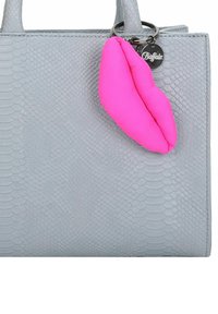 Borsa grigia con texture e motivo in pelle di serpente, con un charm a forma di labbra rosa su un anello d'argento. L'etichetta del marchio dice "Buffalo".