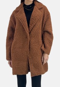 Bruine, pluizige oversized jas van gestructureerd materiaal, met een kraag met inkeping en grote revers, gesloten zonder zichtbare knopen.