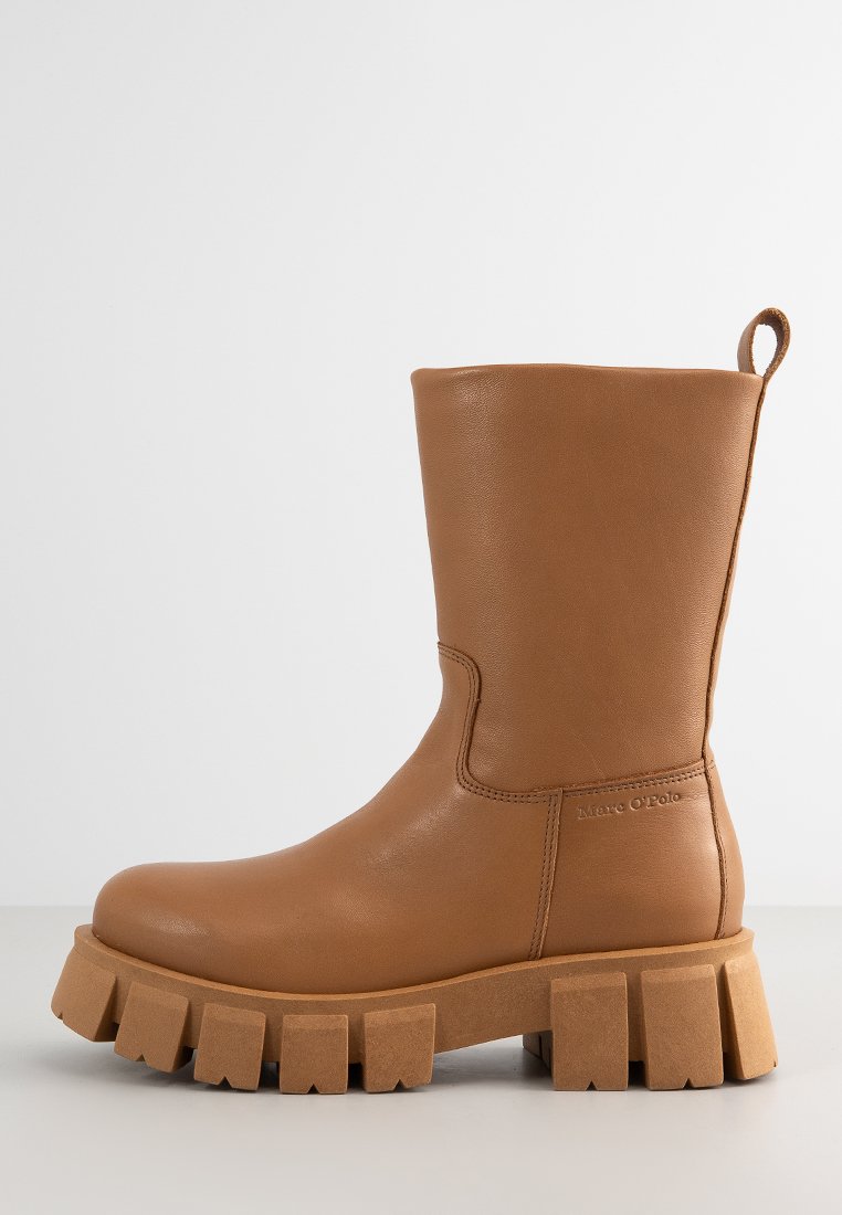 Braune Leder-Stiefeletten mit einer klobigen beigen Plateausohle und einem seitlichen Zugband für einfaches An- und Ausziehen. Glatte Textur mit minimalistischem Design.