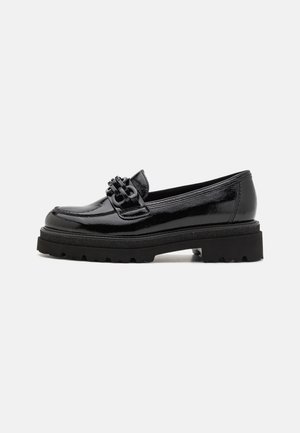 Black patent leather loafers with a chunky black outsole, featuring a decorative strap and buckle detail on the upper.