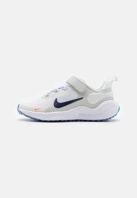 Zapatilla deportiva blanca con una parte superior de malla, acentos sintéticos grises, suela azul y una correa de velcro. Presenta un logo marino y detalles naranjas.