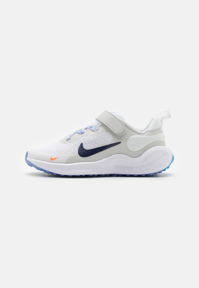 Zapatilla deportiva blanca con una parte superior de malla, acentos sintéticos grises, suela azul y una correa de velcro. Presenta un logo marino y detalles naranjas.