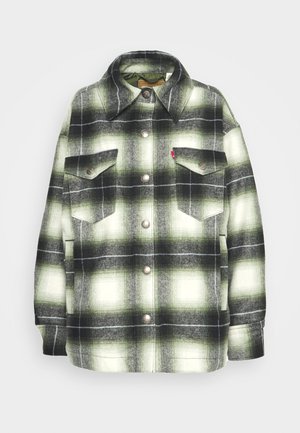 Black and green plaid flannel shirt with two chest pockets, metal buttons, and a pointed collar. Soft texture with a vintage style.