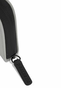 Neceser abotonado en gris y negro con un exterior suave, tela texturizada y una etiqueta negra con marca en relieve.