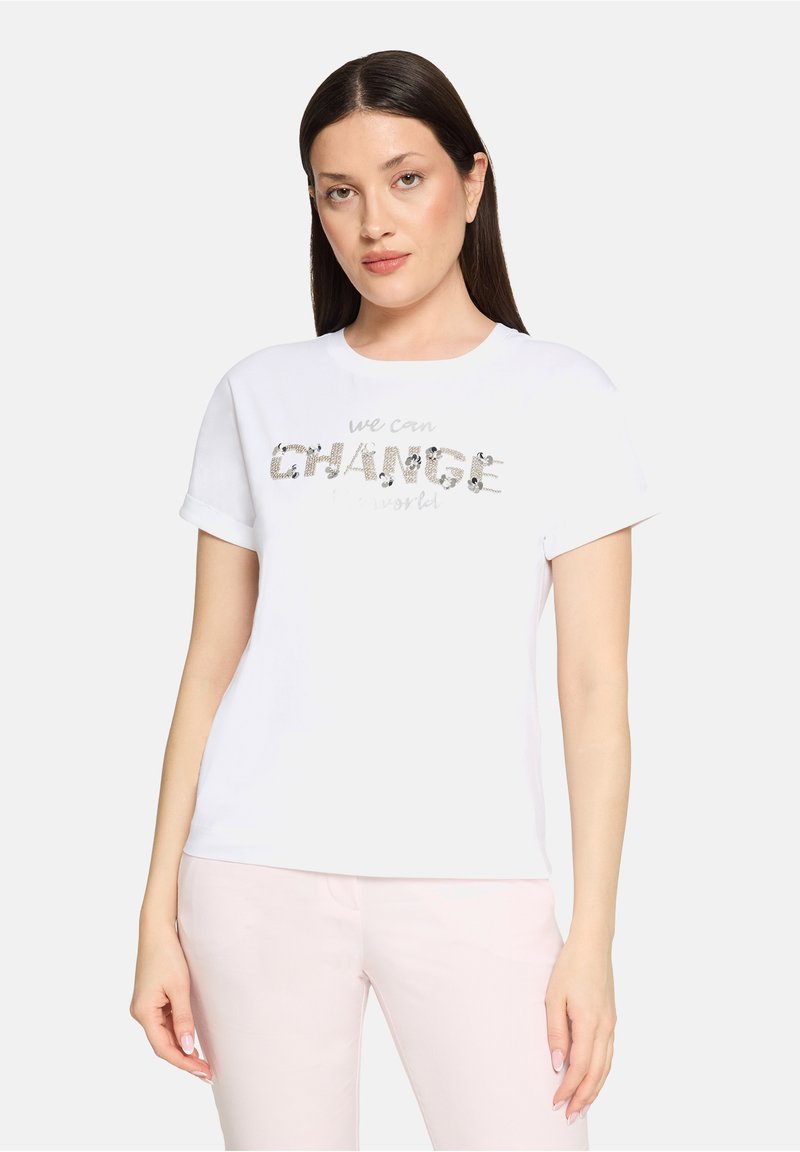 T-shirt en coton blanc avec un motif "CHANGE" en sequins argentés dans une police audacieuse, manches courtes retroussées et coupe décontractée.
