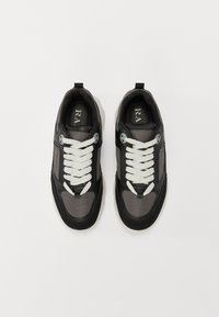 Schwarze und graue Turnschuhe mit Mesh-Einsätzen, weißen Schnürsenkeln, einer runden Zehenpartie, gepolstertem Kragen und einer markierten Innensohle. Gummisohle mit strukturierten Details.