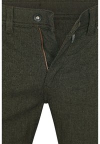 Donkergroene broek van gestructureerde stof, met een ritssluiting en knoop, zichtbare stiksels en een klassiek ontwerp.