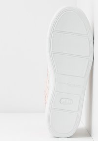 Sneaker rose texturé avec semelle en caoutchouc blanc. Présente un design tissé et des bords lisses sur la partie supérieure. Style épuré et minimaliste.